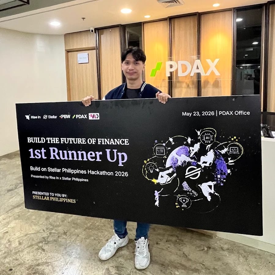 Mychal Pejana holding the "Build the Future of Finance — 1st Runner Up" board at the PDAX office, May 23, 2026