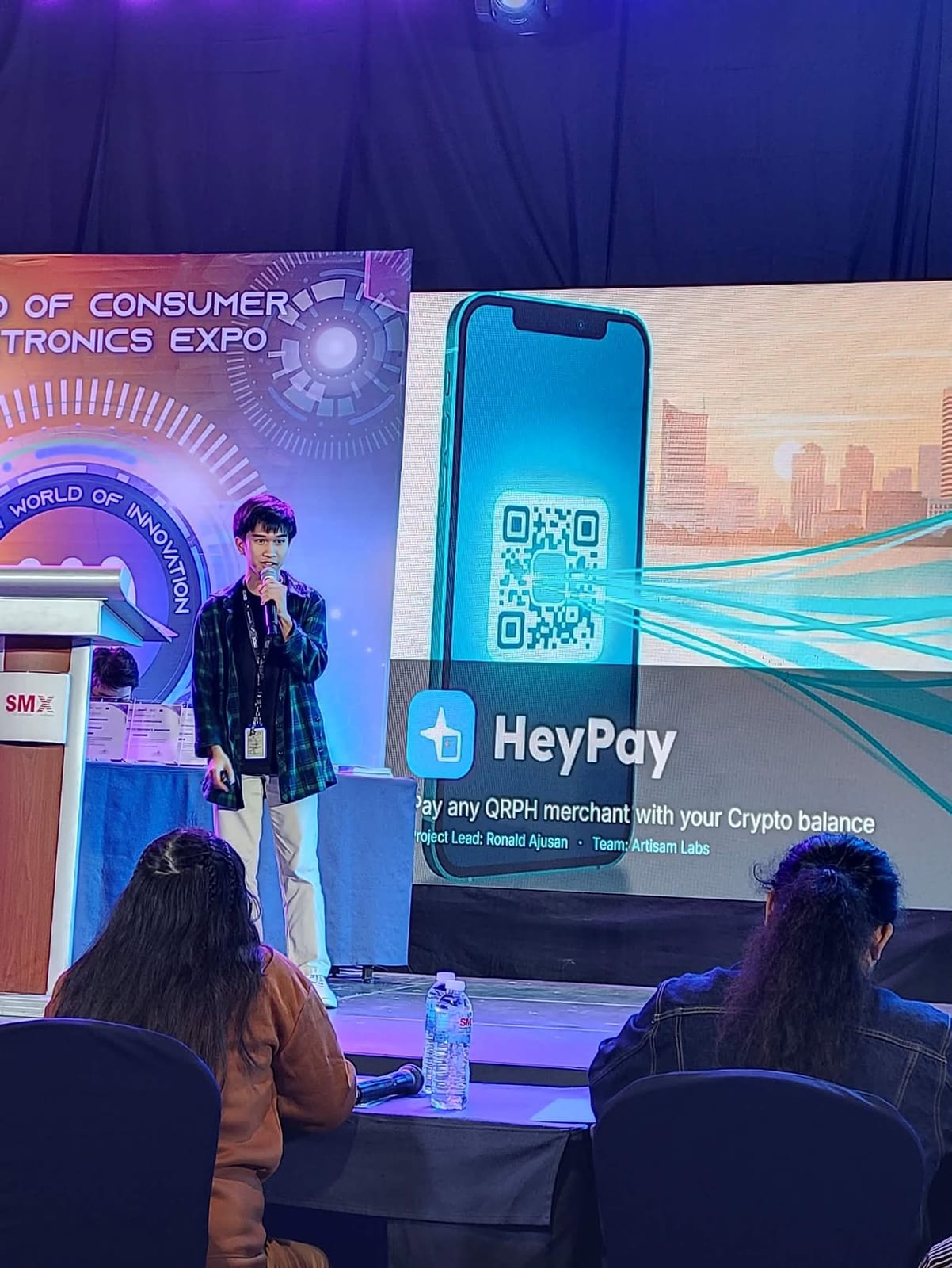 The HeyPay pitch on the WOCEE 2026 main stage, with the product slide on screen